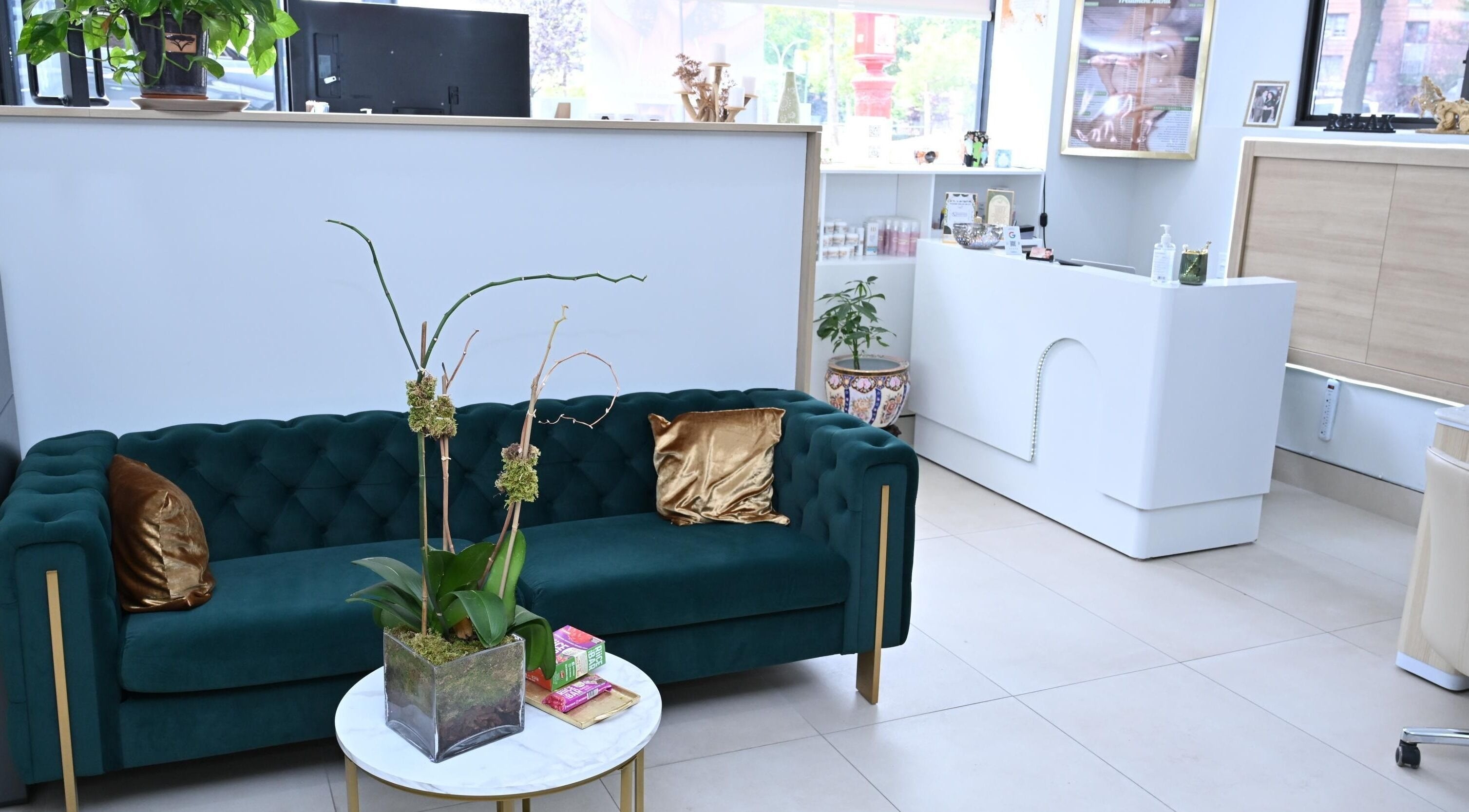 Luxurious lounge area at Laura's Beauty Touch, Rego Park, NY, featuring a green velvet sofa and chic decor.