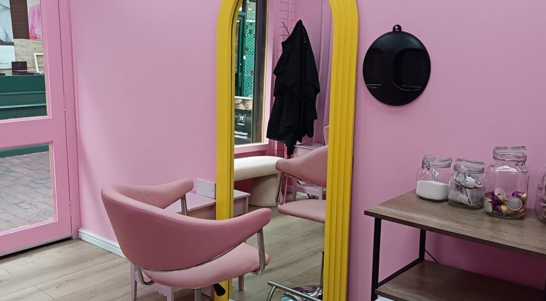 Chic pink interior at Franks salon, Cheadle, England, GB with stylish seating and decorative jars on shelf.