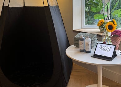 Spray tan booth at Bronzed by Chlo in Manchester, England, GB with towels, products, and floral decor.
