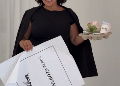Smiling person at The SKVN Studio, Fleming Island, Florida, holding a gift tray with flowers and a card.