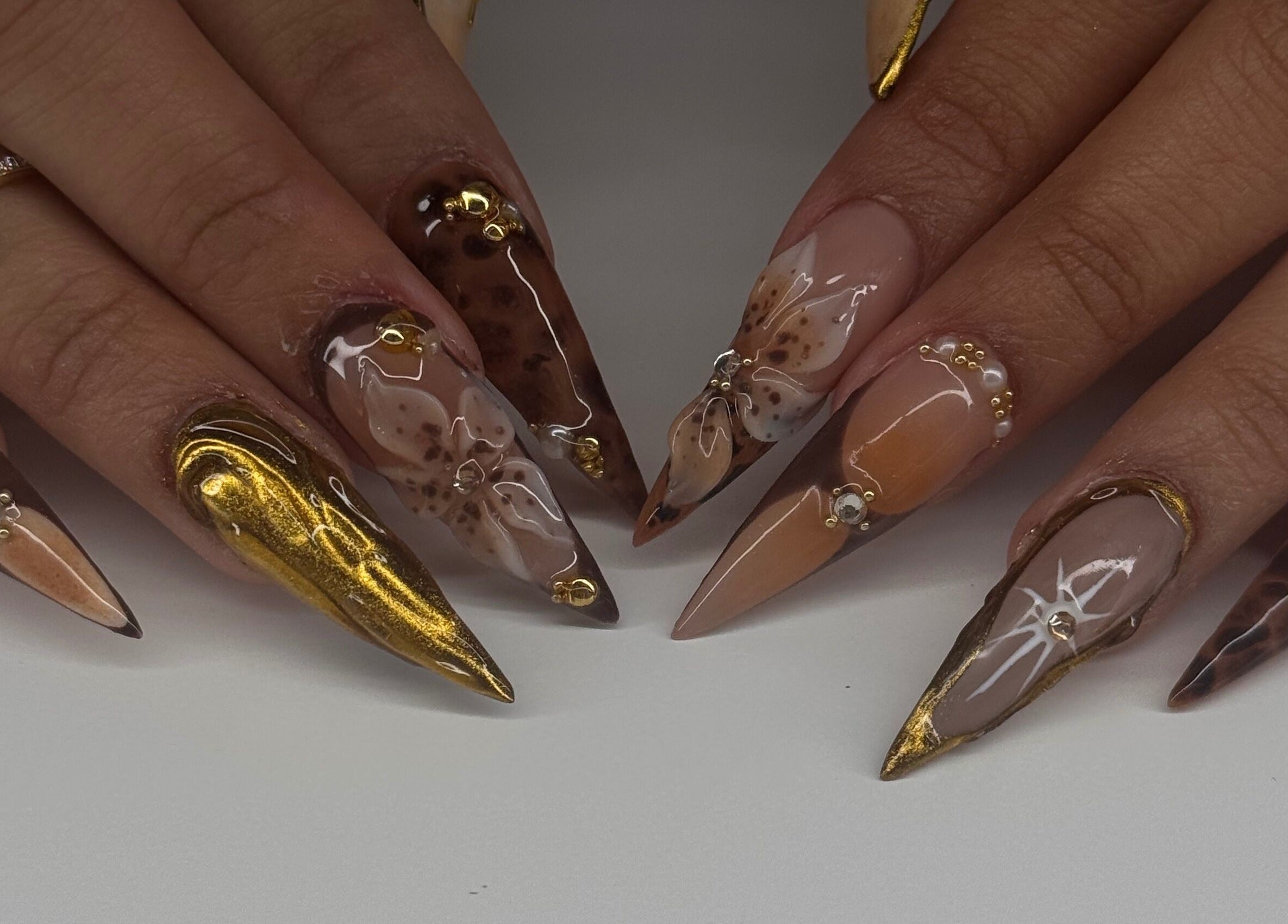 Exquisite gold and floral nail art at Manis & Minks, Montréal, Québec, CA, showcasing intricate designs.