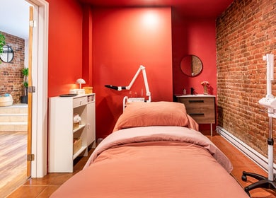 Salle de soins chaleureuse chez État Sauvage, Montréal, Québec, CA, avec murs en briques et lit de détente.