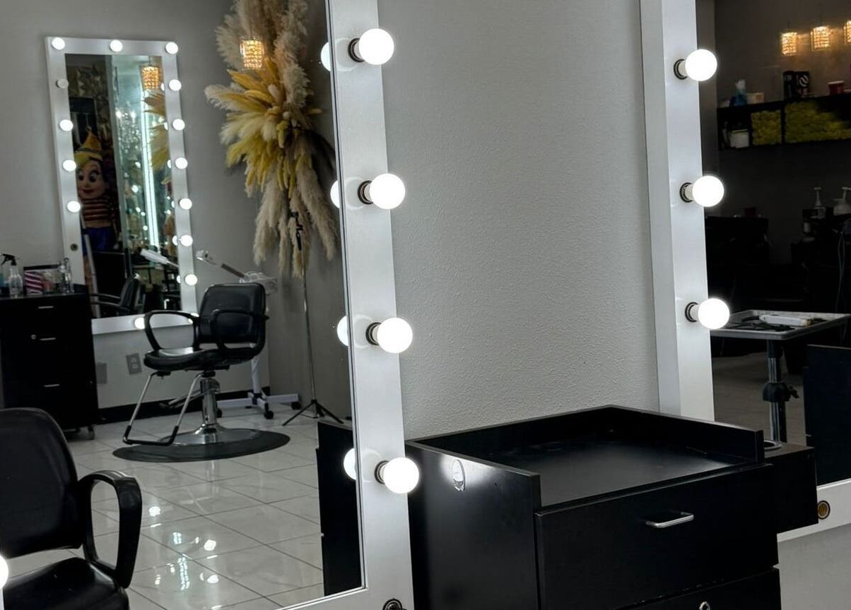 Espejo iluminado en el interior de By Cantu Salón, Dallas, Texas, US, mostrando una silla de estilista.