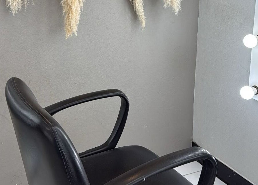 Silla de peluquería moderna junto a espejo iluminado en By Cantu Salón, Dallas, Texas, US.