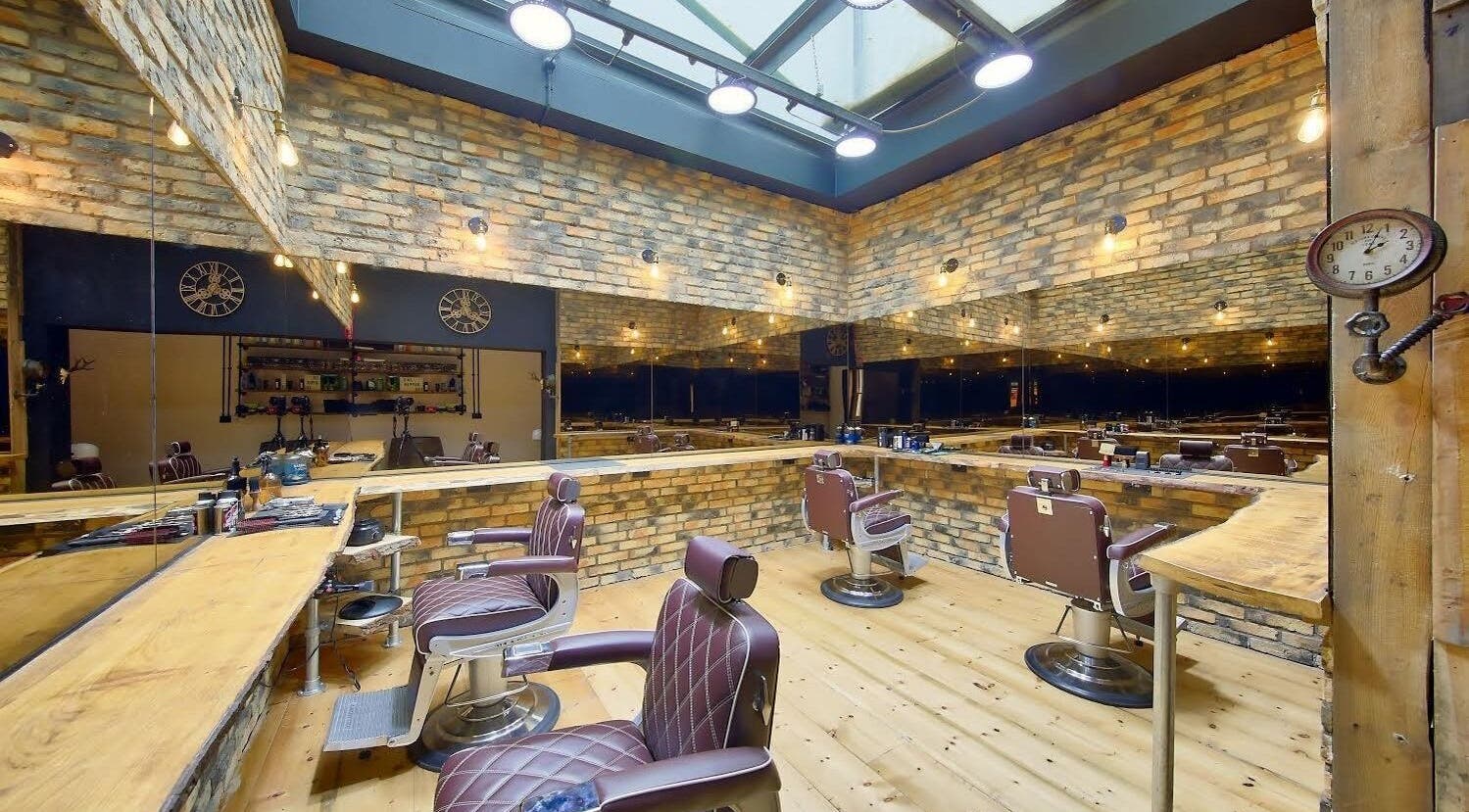 Spacious interior of The Dapper Fox - Wandsworth, showcasing modern barber chairs and rustic brick walls in London, England, GB.