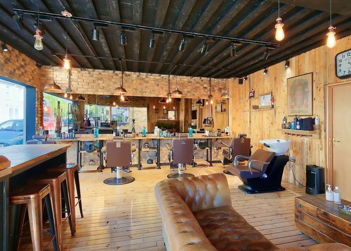 Interior of The Dapper Fox - Hampton Wick, a rustic salon in Hampton Wick, England, GB with leather seating and barber chairs.