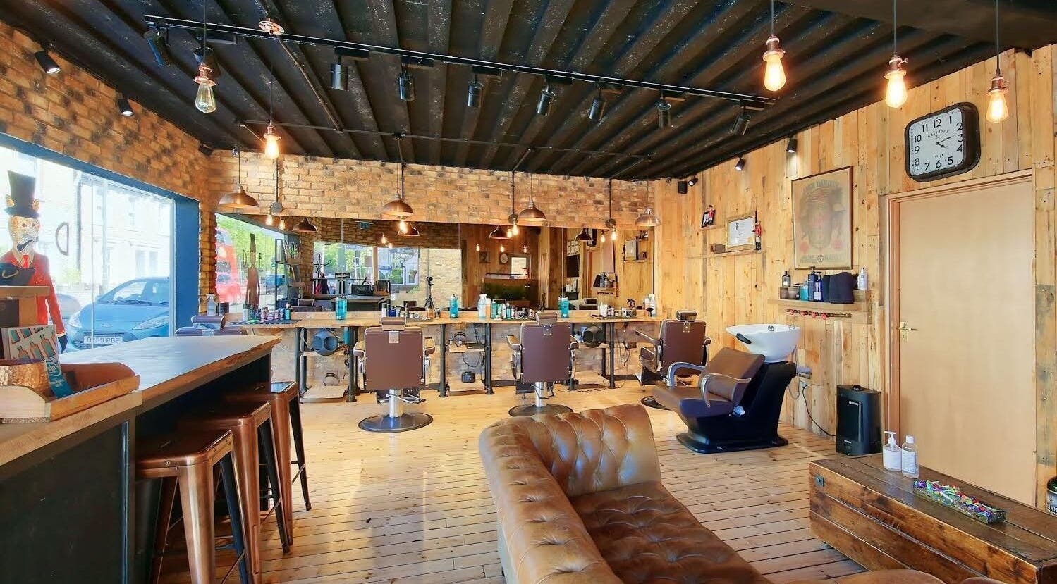 Interior of The Dapper Fox - Hampton Wick, a rustic salon in Hampton Wick, England, GB with leather seating and barber chairs.
