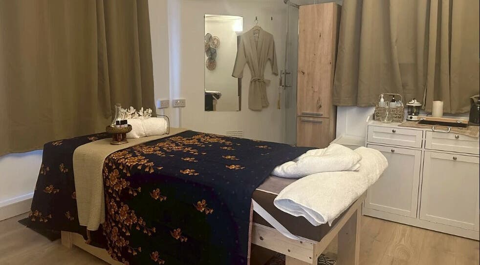 Cozy massage room at Suk Jai Richmond Thai Massage in Richmond, England, GB with a decorated bed and warm lighting.