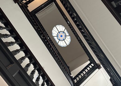 Ornate staircase at Christina Bethany, London, England, GB with intricate stained glass ceiling.