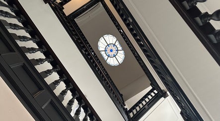Ornate staircase at Christina Bethany, London, England, GB with intricate stained glass ceiling.