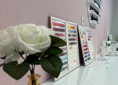 Bảng màu sơn móng tay tại Beauty & More, Frankfurt Am Main, Hessen, DE, với hoa hồng trắng trang trí.