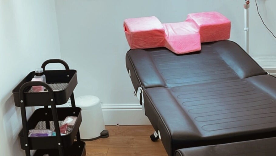 Sala de tratamento na Beauty Vanessa Tavares em Dublin, County Dublin, IE, com mesa e almofadas rosas.