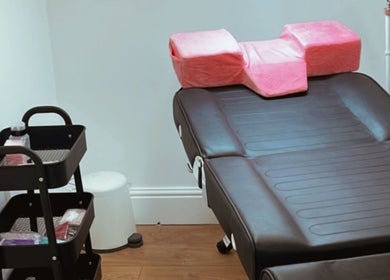 Sala de tratamento na Beauty Vanessa Tavares em Dublin, County Dublin, IE, com mesa e almofadas rosas.