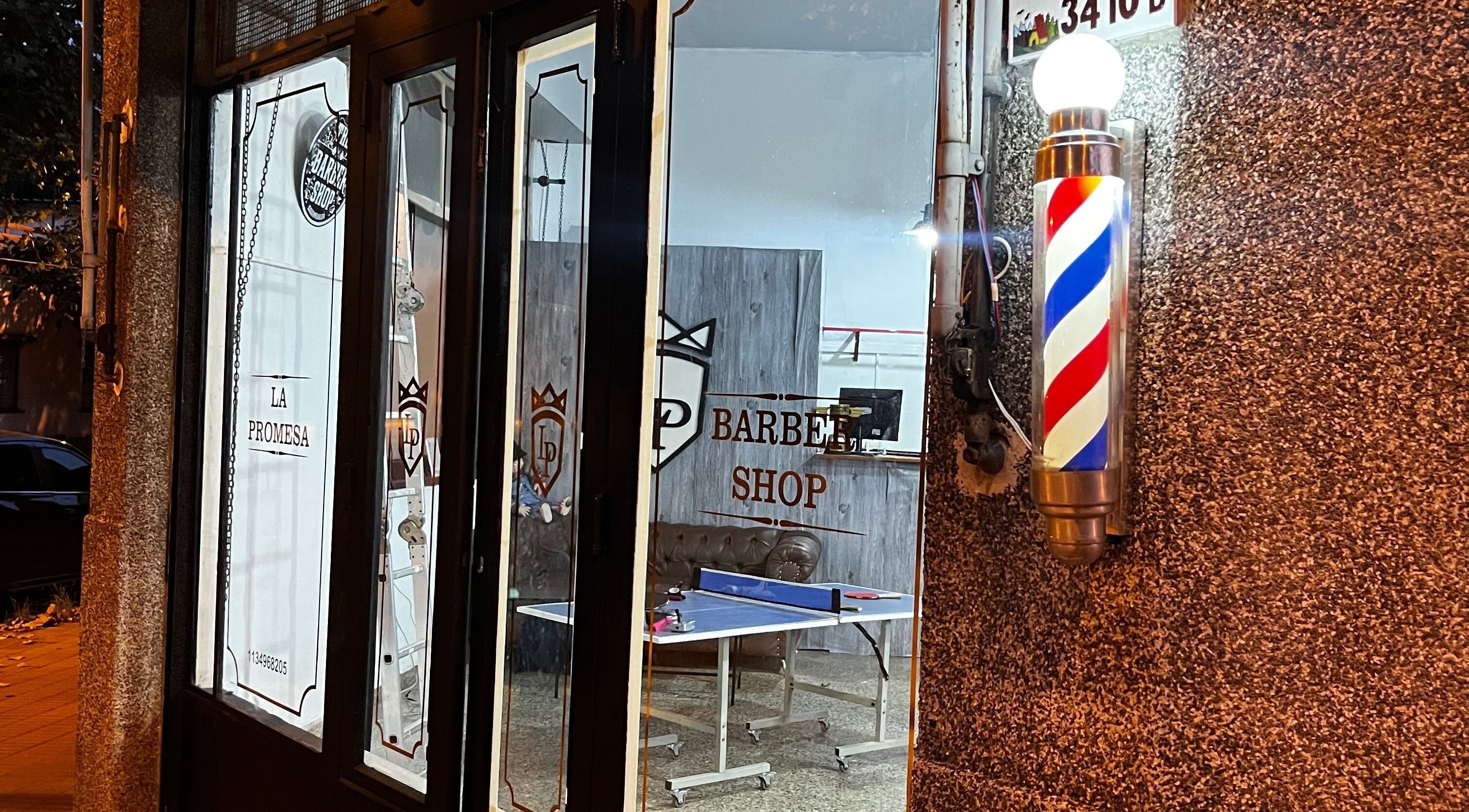 Entrada de La promesa SA, Villa San Andrés, Provincia De Buenos Aires, con cartel de barbería iluminado.