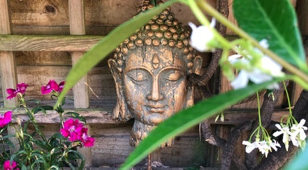 Buddha statue in garden at Bespoke Wellness & Academy, Dublin, County Dublin, IE surrounded by vibrant flowers.