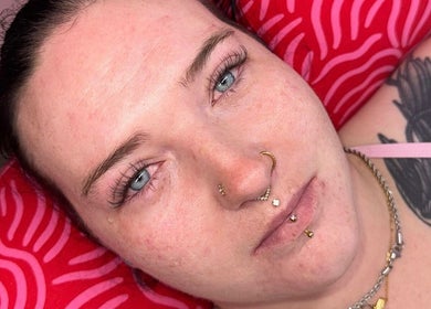 Relaxed individual at LCH BEAUTY, Dalkeith, Scotland, GB, showcasing facial piercings and tattoos.