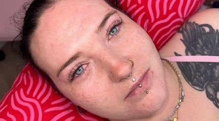 Relaxed individual at LCH BEAUTY, Dalkeith, Scotland, GB, showcasing facial piercings and tattoos.