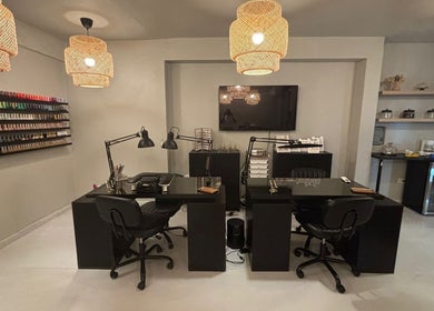 Estación de manicura moderna en Oasis Nails Spa, San Juan, PR, con lámparas colgantes y amplia selección de esmaltes.
