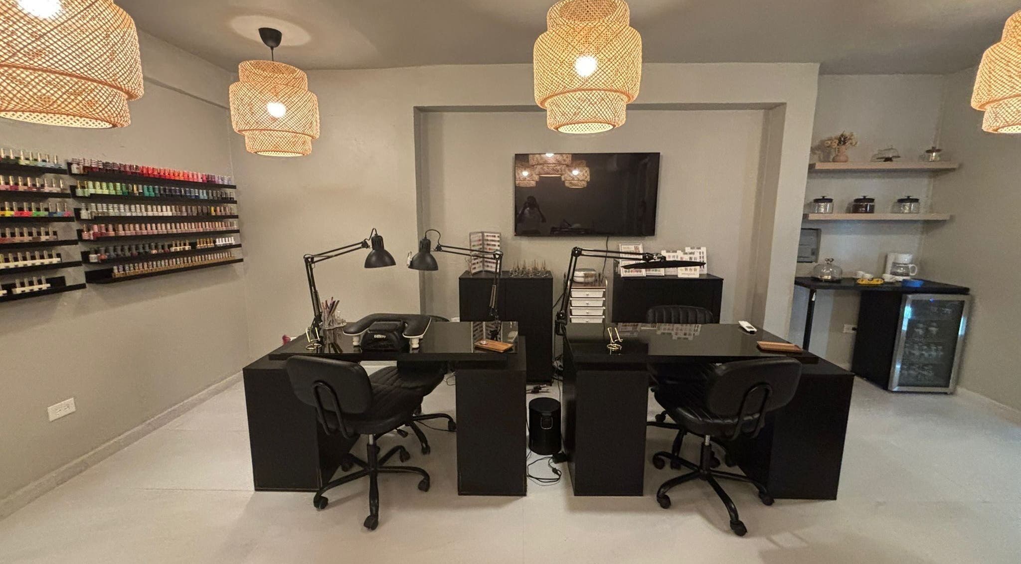 Estación de manicura moderna en Oasis Nails Spa, San Juan, PR, con lámparas colgantes y amplia selección de esmaltes.