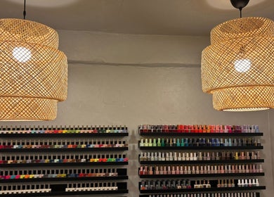 Estante de esmaltes de uñas bajo luz ambiental en Oasis Nails Spa, San Juan, PR.