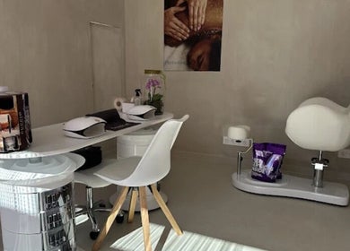 Interior de Cocoon’ink Wellness Studio, Mataró, Catalunya, ES: sillas blancas y estación de masaje.