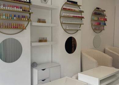 Elegant nail salon interior at Shiny Nails, London, England, GB showcasing cozy chairs and colorful polish displays.