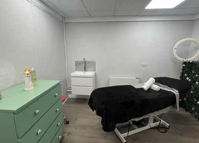Relaxing treatment room at Get Em Treatments in Aberdeen, Scotland, GB with a floral wall and massage bed.