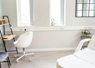 Bright treatment room at Weymouth Aesthetics Clinic, Weymouth, England, GB with stylish decor and white chairs.