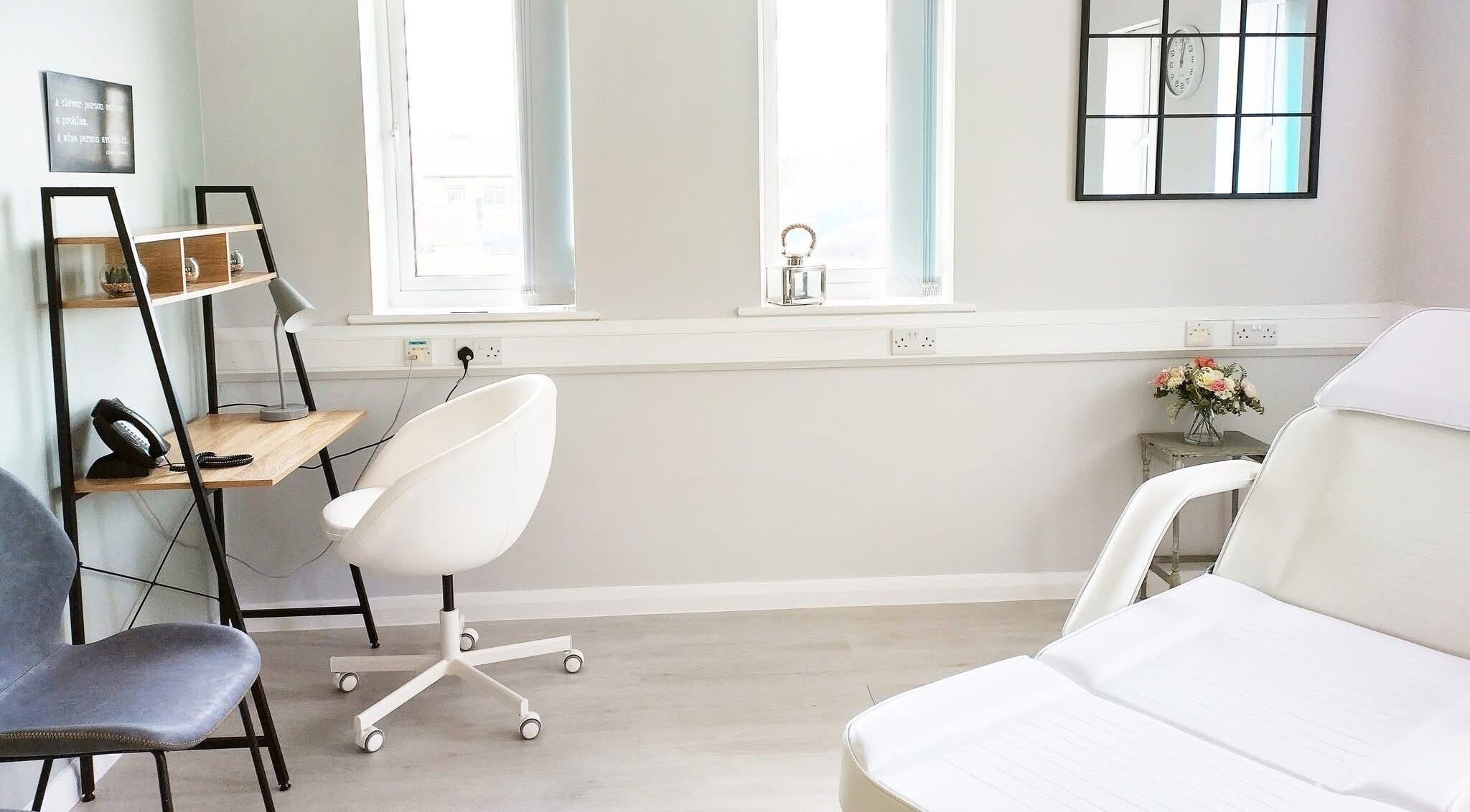Bright treatment room at Weymouth Aesthetics Clinic, Weymouth, England, GB with stylish decor and white chairs.