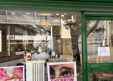 Front view of USA Star Beauty, London, England. Features window decor and services poster.