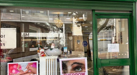 Front view of USA Star Beauty, London, England. Features window decor and services poster.
