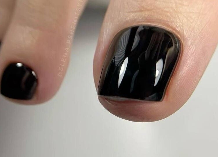 Sleek black polished toenail at Vicky’s Nails in Gendros, Wales, GB, showcasing expert pedicure skills.