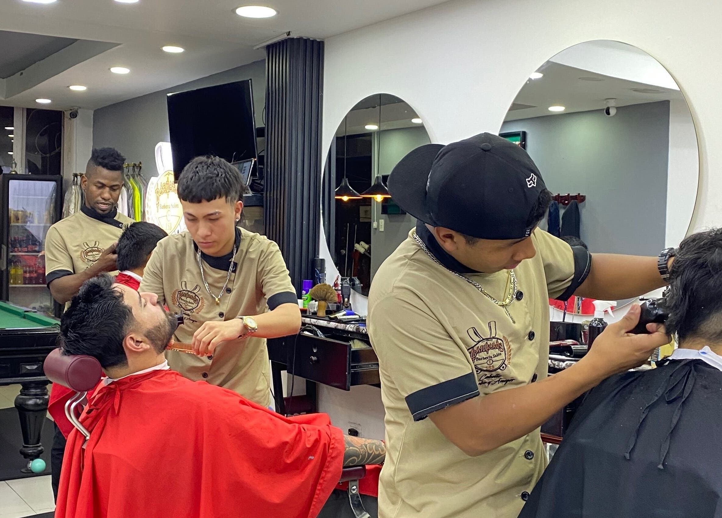 Estilistas trabajando en Q'Barbaros en Bogotá, Bogotá, CO, ofreciendo cortes de cabello profesionales.