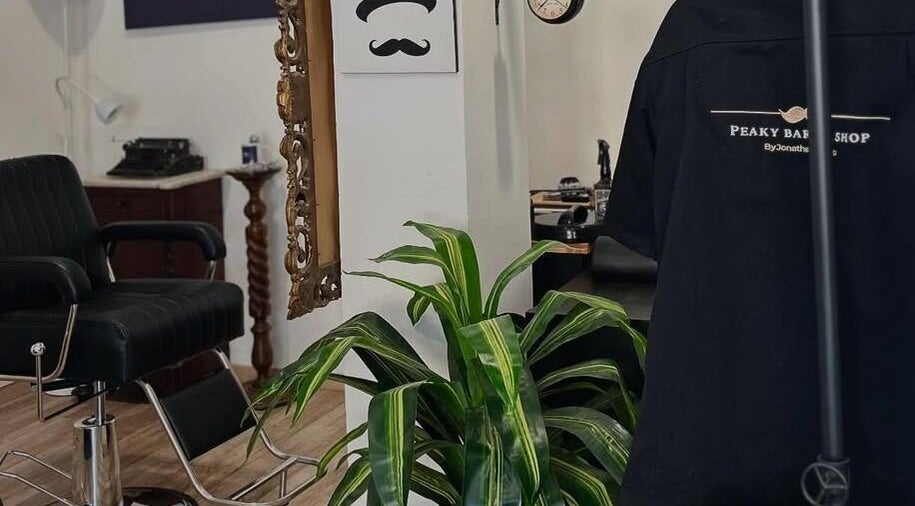 Interno del Peaky Barber Shop by Jonathan Di Tizio a Livorno, Toscana, IT, con arredi eleganti e pianta verde.