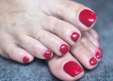 Close-up of red polished toenails at Oliviabeautè, Eastbourne, England, GB. Luxurious pedicure experience.