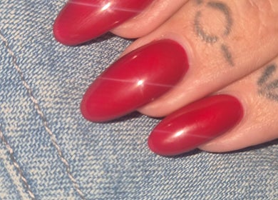 Red polished nails on denim background at Oliviabeautè, Eastbourne, England, GB.