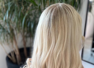 Blonde hair styled at Blended Hair & Wellness, Hounslow, England, GB with plants in the background.