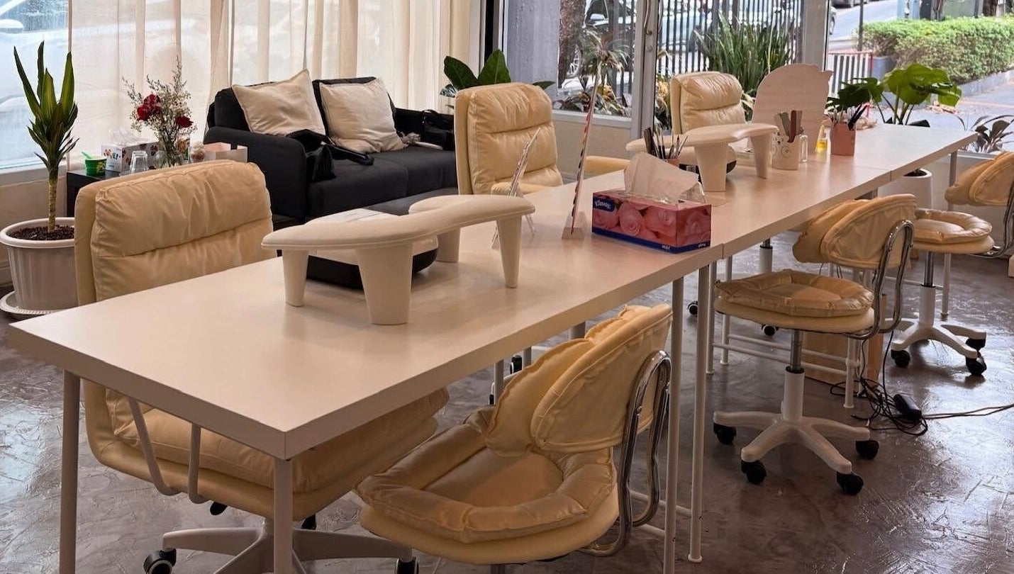 Spacious manicure area at YIN Nails and Lashes, Krung Thep Maha Nakhon, with beige chairs and white tables.