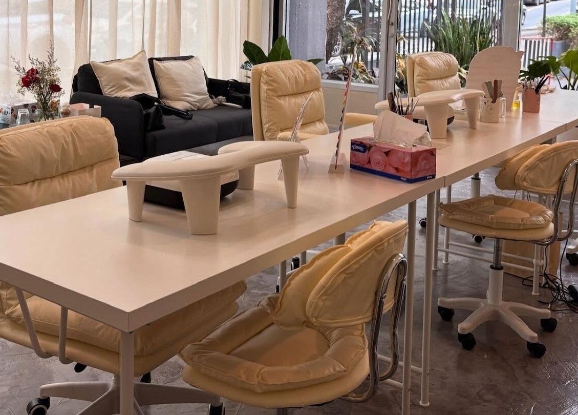 Spacious manicure area at YIN Nails and Lashes, Krung Thep Maha Nakhon, with beige chairs and white tables.
