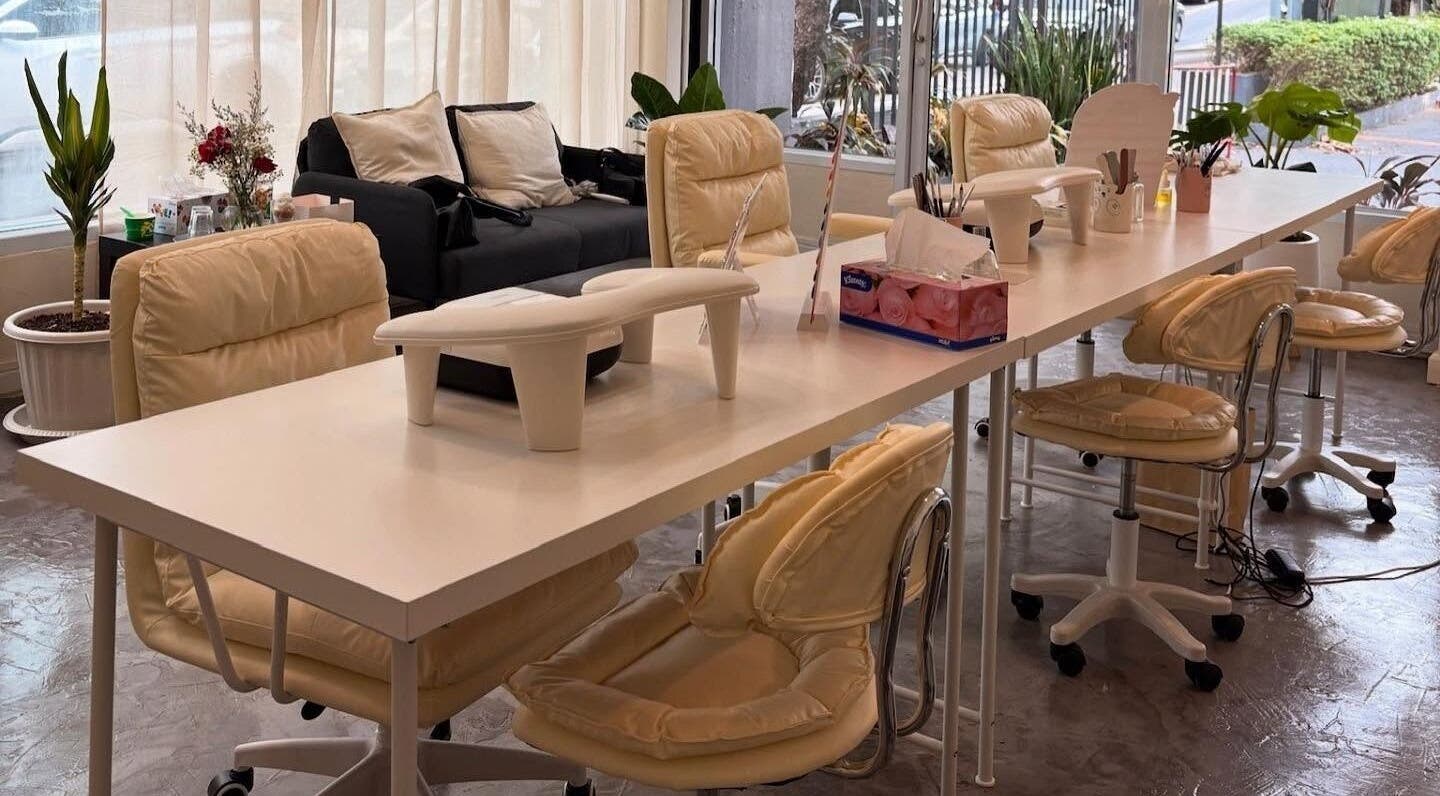 Spacious manicure area at YIN Nails and Lashes, Krung Thep Maha Nakhon, with beige chairs and white tables.