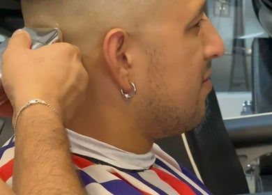 A skilled barber trims hair at Alberto's Barber and Wellness Hub, Gzira, MT, providing exceptional grooming services.