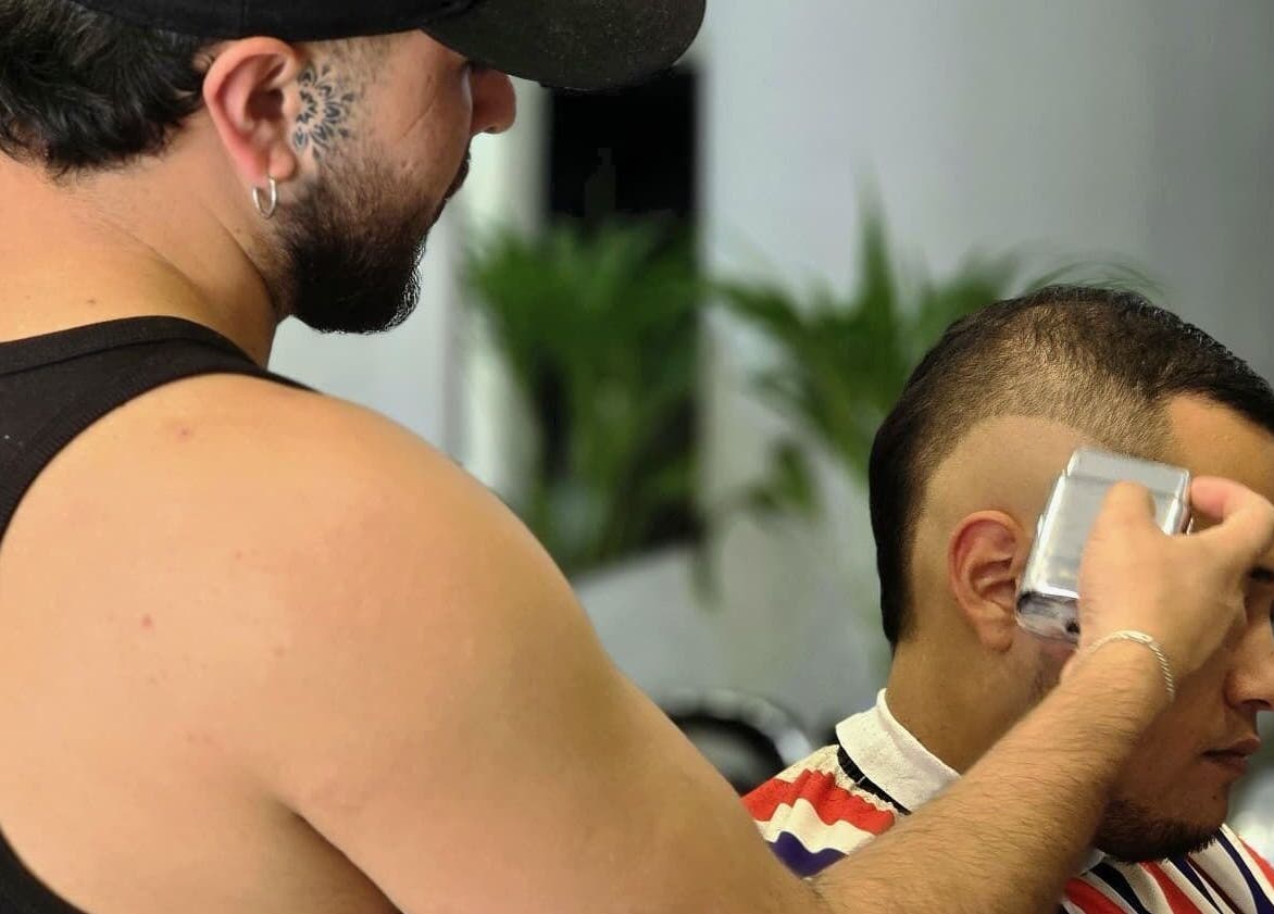 Barber expertly trimming hair at Alberto's, Gzira, MT. Experience precise cuts and styling in a modern setting.