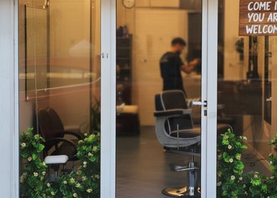 Front entrance of Alberto's Barber Shop, San Ġiljan, MT with inviting decor and visible barber chair.