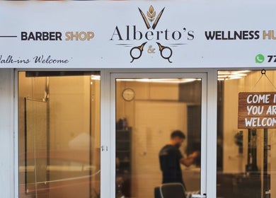 Entrance to Alberto's Barber Shop in San Ġiljan, MT showcasing inviting sign and decor.