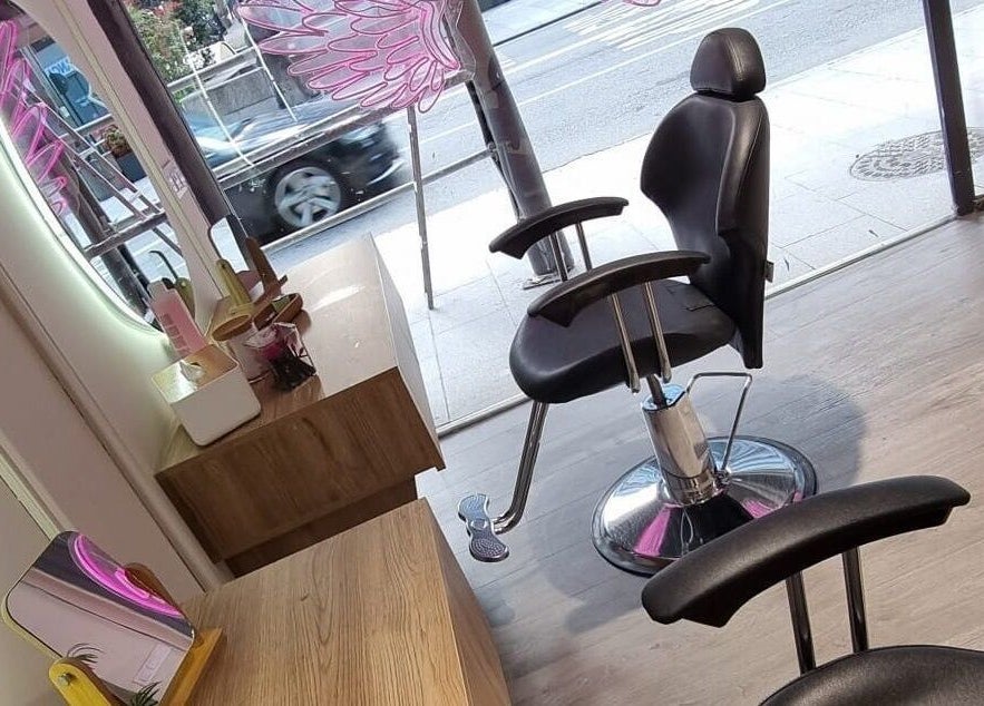 Silla de salón en Clinic Nails, Vigo, ES, junto a espejo iluminado y decoración moderna.