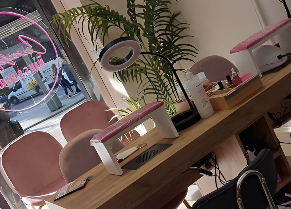 Mesa de manicura en Clinic Nails, Vigo, ES, con sillas rosadas y herramientas de belleza.