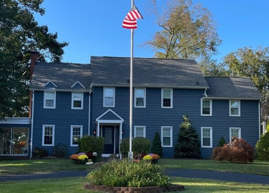 Front view of BEC Nail Studio LLC in Seaford, Delaware, US, showcasing a classic blue exterior and lush greenery.