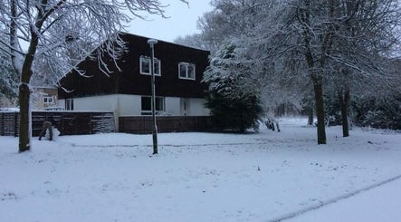 Winter landscape at Fern & Flow Massage, Clydebank, Scotland, GB, showcasing a snow-covered building and trees.