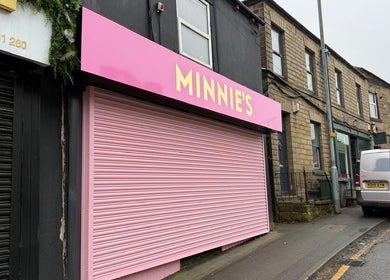 Pink storefront of Minnie's in Birstall, England, GB, showcasing its vibrant exterior.
