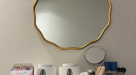 Елегантне дзеркало у Sugar&lashroom, Calgary, Alberta, CA з косметичними продуктами на столику.